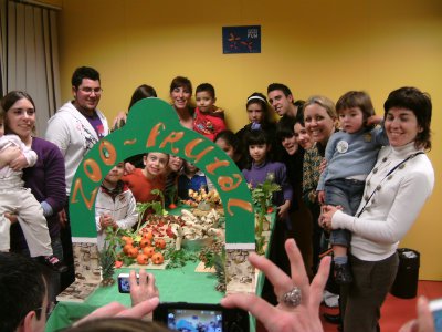 Group of people gathered around table with green paper arch reading "Zoo Frutal" at the CAP Murallas fruit zoo workshop.