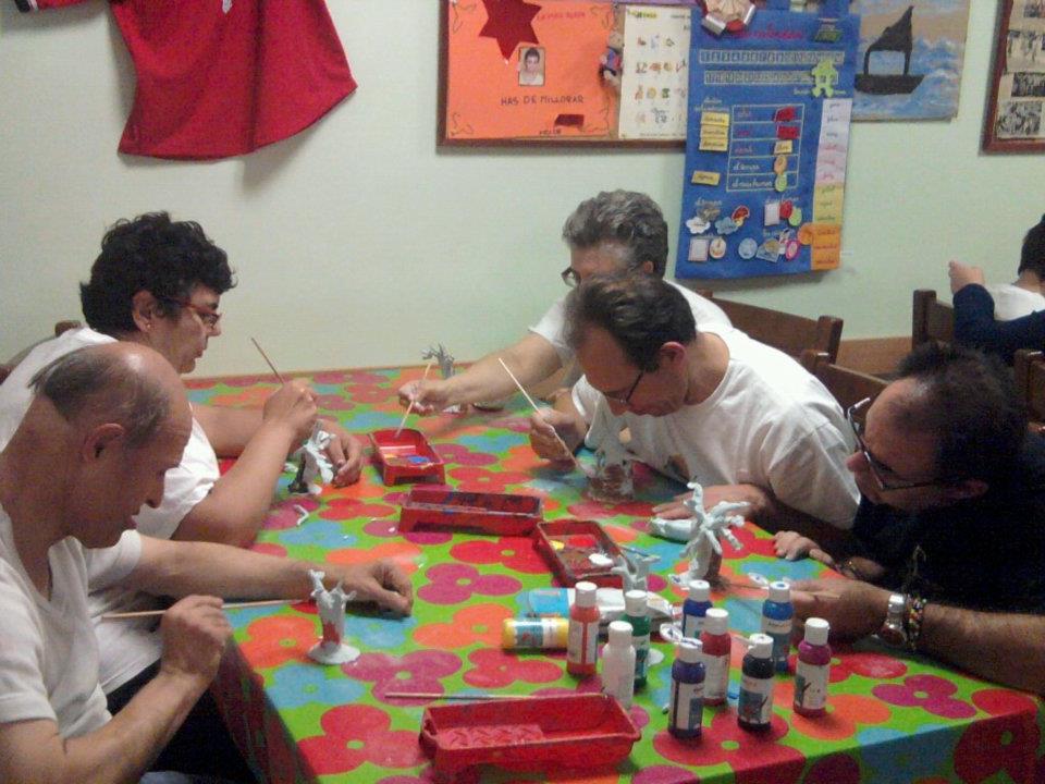 Group of people sitting at a table painting clay trees