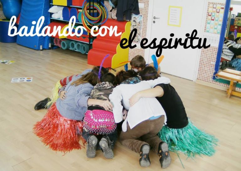 Children huddled together on wooden dancefloor with overlaying text reading "bailando con el espiritu" (dancing with spirit)