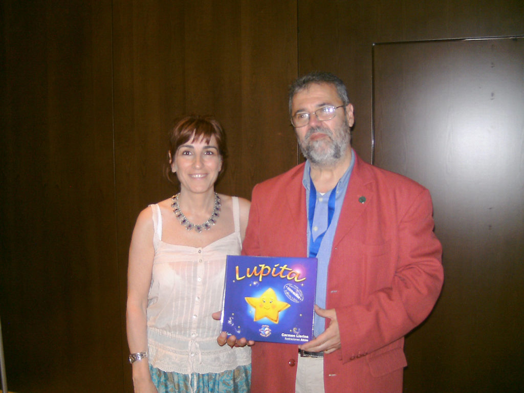 Lia with man in a red jacket holding a copy of the book "Lupita"