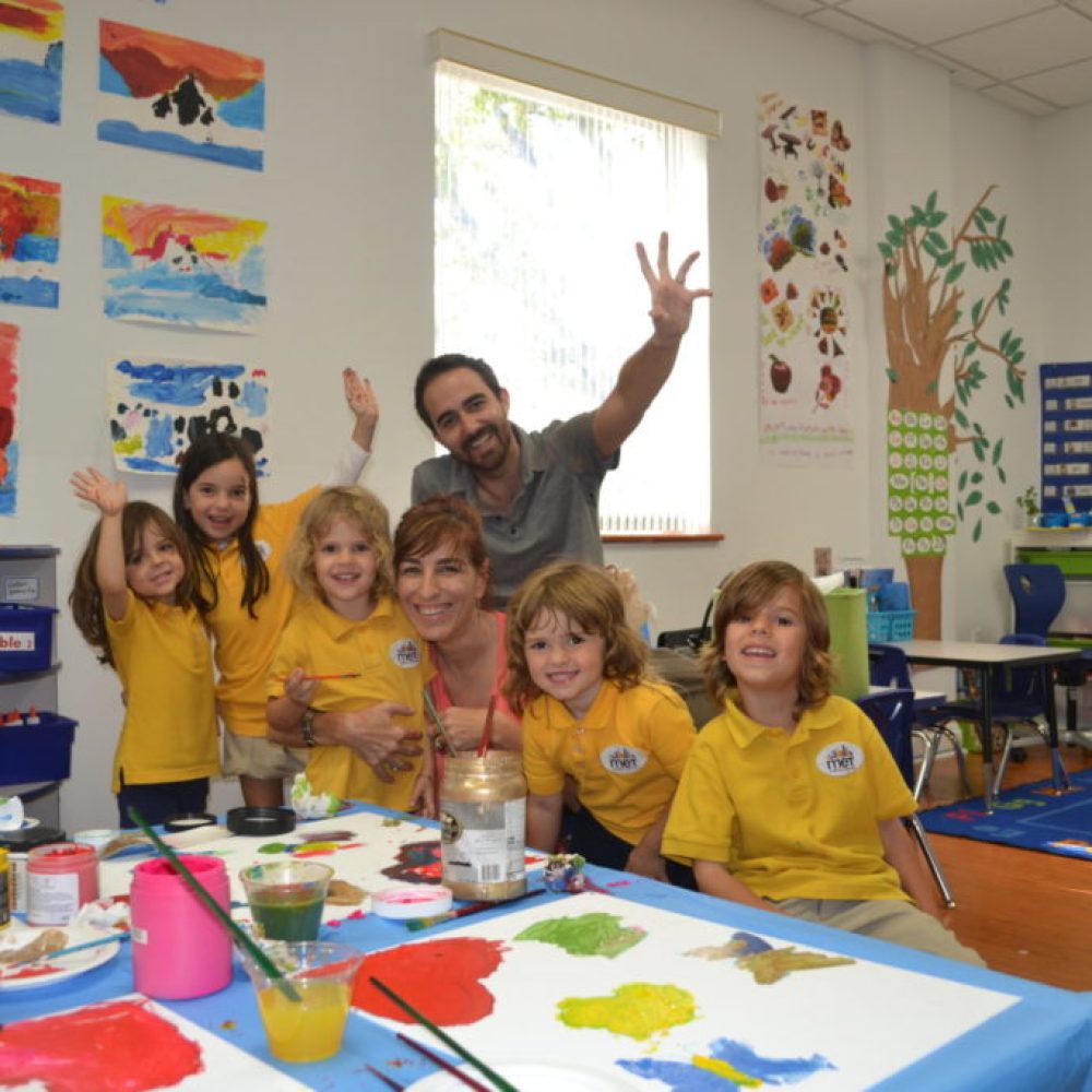 Photograph of founders Lia and Kyn with group of young children in their classroom