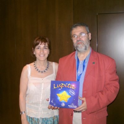 Lia with man in a red jacket holding a copy of the book "Lupita"